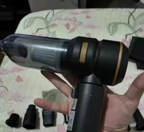 Customer photo holding the black cordless unit with its nozzles and filters on a bedspread